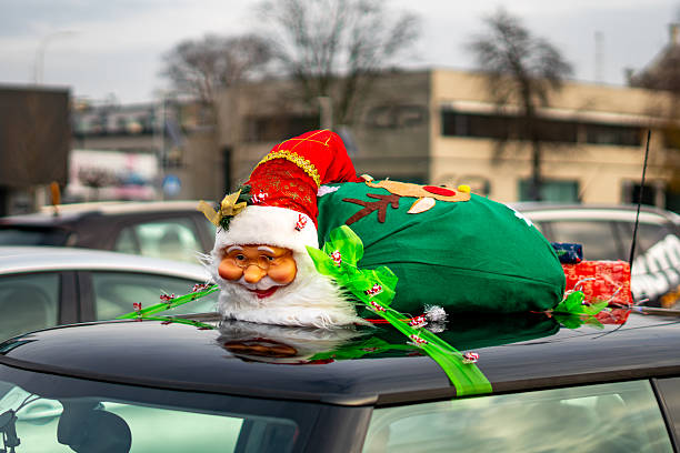Christmas decoration featuring a Santa figure with red hat and green sack displayed on a vehicle during a festive holiday parade