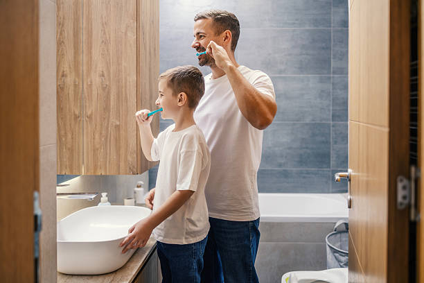 istock Father and son brushing teeth together in bathroom 2250494352