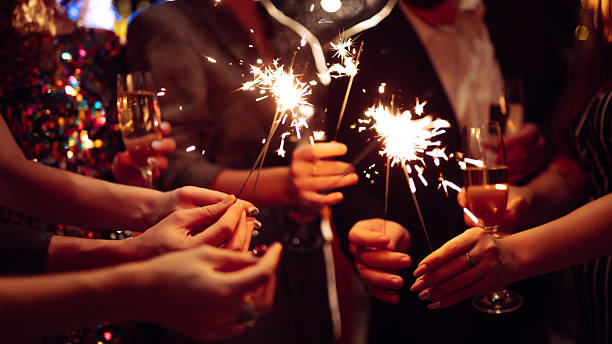 istock A happy group is having fun at a bar, drinking drinks, and lighting sparklers in a cozy space. 2250498144