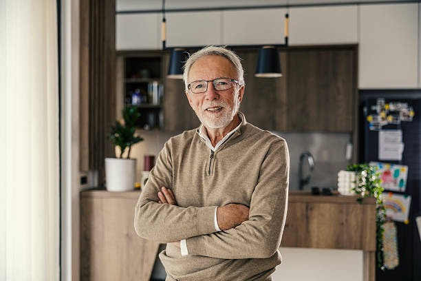 istock Senior man smiling with arms crossed in modern home kitchen 2250498541