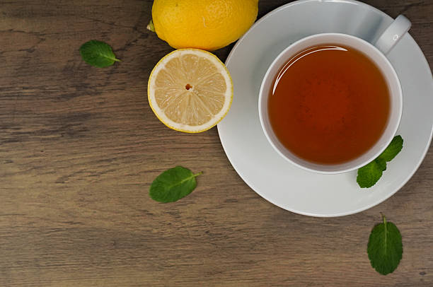 Tasty mint tea in cup, lemon and fresh leaves on wooden table, flat lay. Space for text