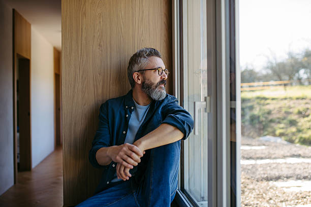 istock Middle aged man sitting by window and thinking. 2250503459