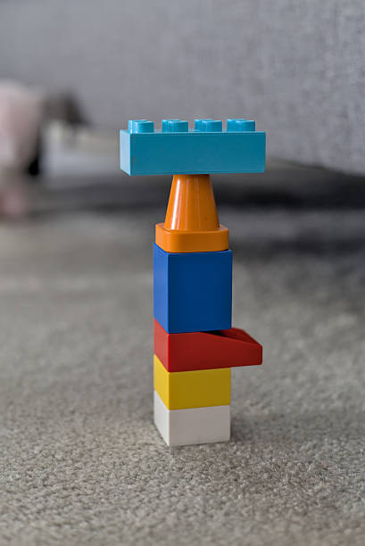 A plastic building block tower sitting on a rug.