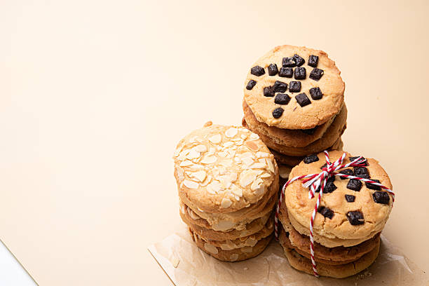 Chunky cookie almond cookie raisin cookie stack bakery dessert sweet homemade rustic golden crumbly buttery crunchy tied parchment snack treat baked sugar flour egg nut dried fruit ribbon gift