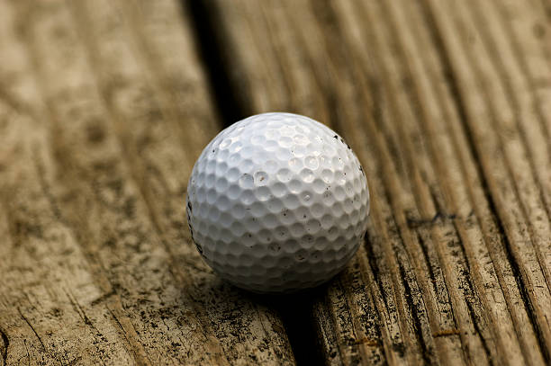 istock Golf Ball Resting on Weathered Bench Near Course 2250506764