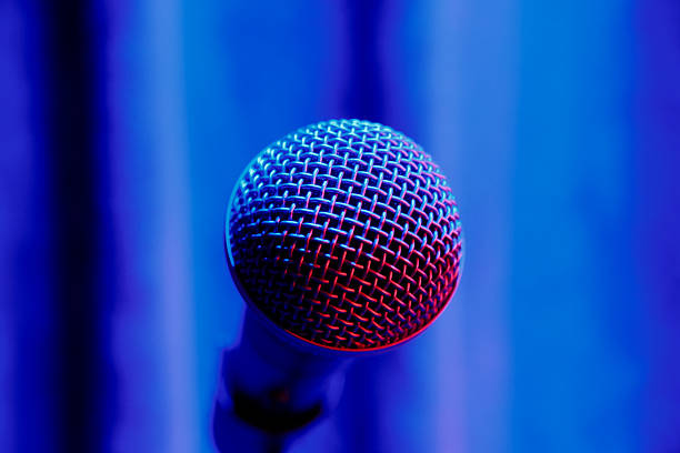 Microphone on stage in red-blue light. A microphone on stage, lit in red and blue, with a curtain backdrop.
