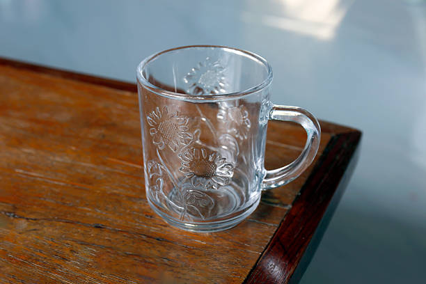 Clear glass cup on wooden table in a minimal setting. Perfect for design projects, lifestyle themes, or beverage related content, close-up