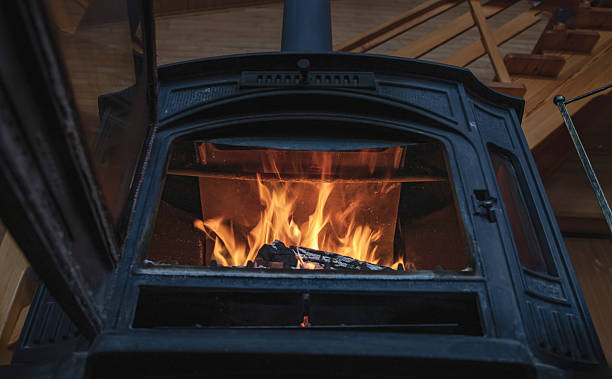 istock Burning firewood inside cast iron stove in cozy rustic wooden home interior 2250513364