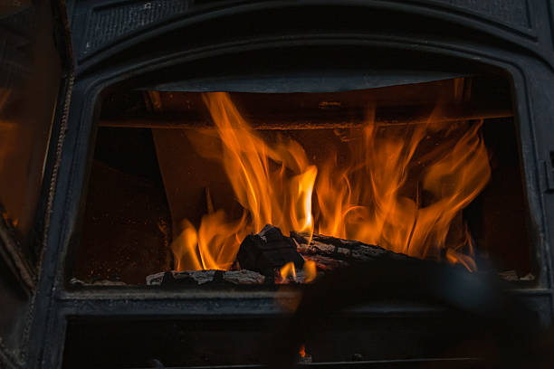 istock Burning firewood inside cast iron stove in cozy rustic wooden home interior 2250513371