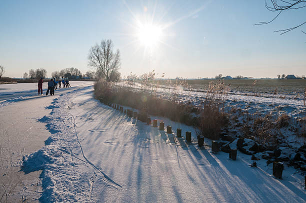 Tytsjerksteradiel, Netherlands - February 4, 2012. Winter scene showing people ice skating on a forzen canal in northern friesland.