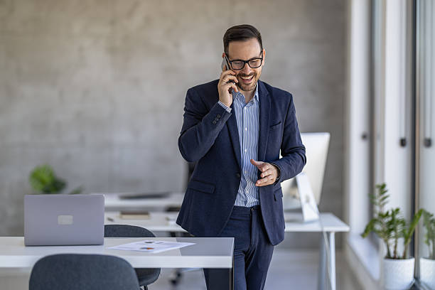 istock Businessman talking on the phone while walking in a modern office during the daytime 2250513927