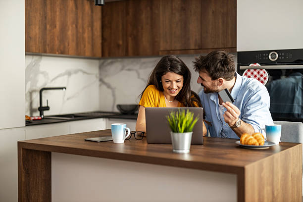 istock Happy couple enjoying morning coffee and working on a laptop in a modern kitchen setting 2250522547