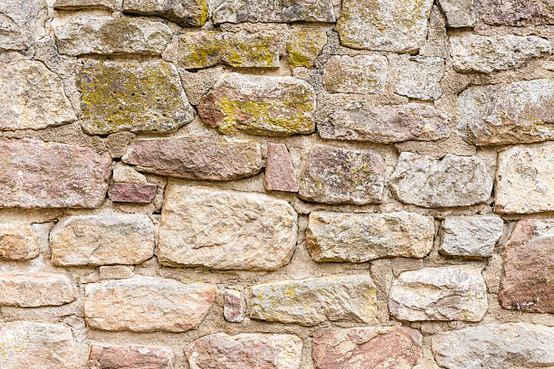 istock Wall or masonry made of sandstone bricks with cracked joints and moss 2250524771