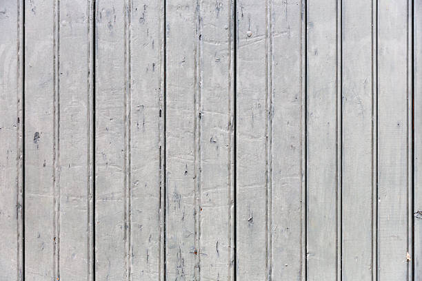 Grey painted wooden wall with pressure marks and paint chips.