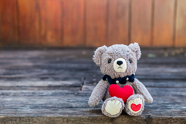 istock Teddy bear and red heart with space on wood background 2250526030