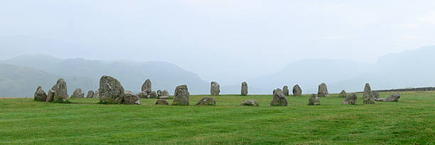 Small axial Drombeg stone circle or The Druid's Altar at Drombeg, Glandore, Cork, Ireland with 13 stones in megalithic ruins with panoramic landscape and cumulus clouds in background