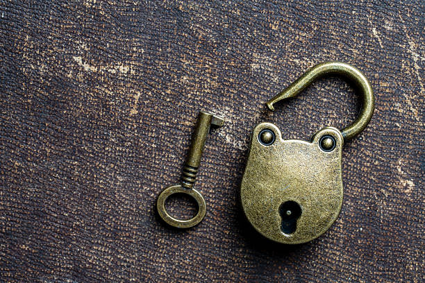 Vintage unlocked padlock and bronze key on a dark background, close up, copy space