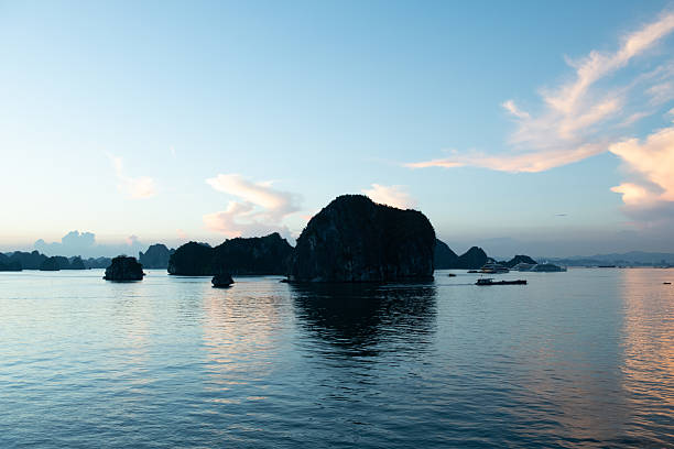 This photograph was taken in Halong Bay in Vietnam. Hạ Long Bay in northeastern Vietnam is known for its emerald waters and thousands of towering limestone islands topped by rainforests. On junk tours and kayak expeditions, visitors navigate islands named after their shape (e.g. Stone Dog and Teapot Islets).