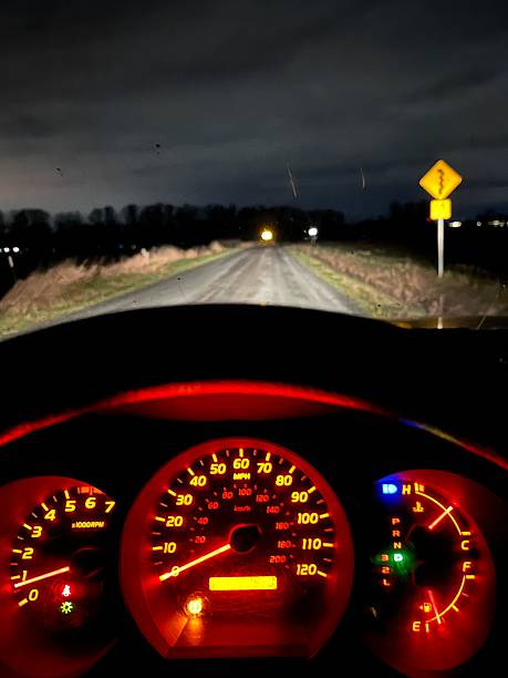 istock A sign indicates sharp curves ahead on a rural road during the night. The area is mostly dark with a few distant lights from nearby buildings. Caution is advised for drivers. 2250544465