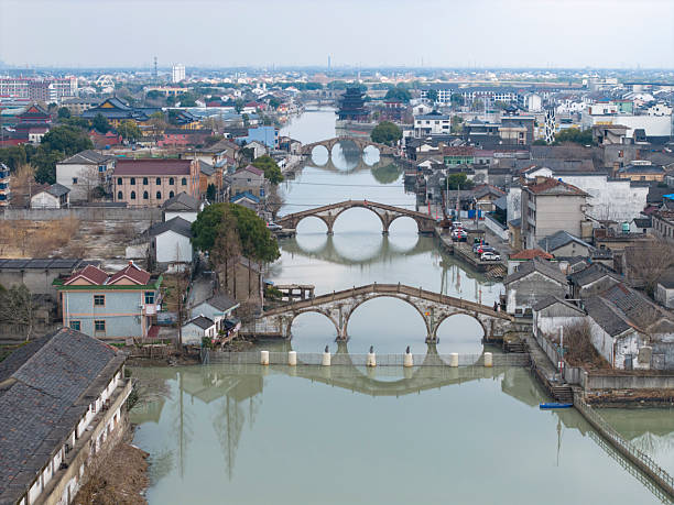 A picturesque view of an ancient town featuring historic stone bridges and canals, showcasing traditional architecture and serene waterways. The visual style is tranquil and nostalgic, ideal for travel or cultural exploration themes.