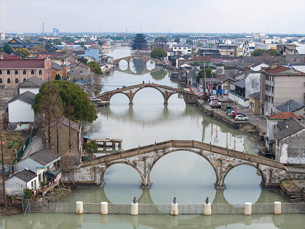 A picturesque view of an ancient town featuring historic stone bridges and canals, showcasing traditional architecture and serene waterways. The visual style is tranquil and nostalgic, ideal for travel or cultural exploration themes.