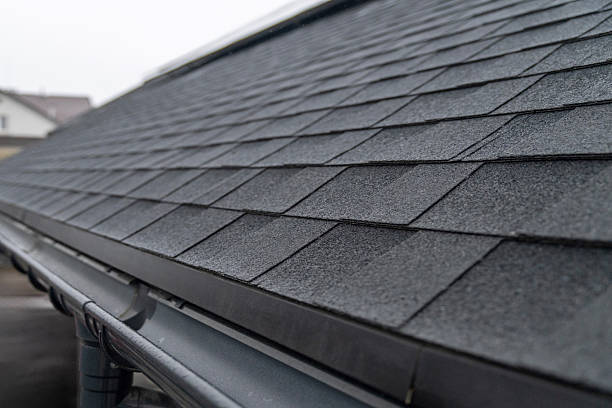 istock Dark gray asphalt roof shingles with rain gutter system close up 2250554051
