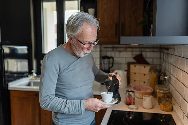 istock Elderly man pouring fresh coffee from a stovetop maker into a cup while standing in a cozy kitchen 2250554071