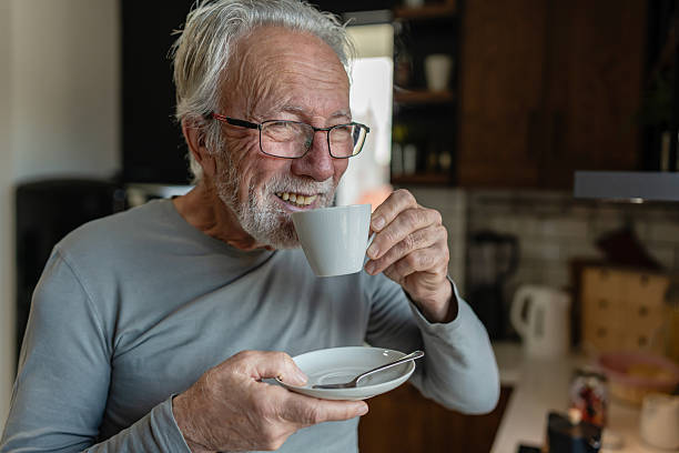 istock Elderly man sipping hot coffee from a cup while standing in a cozy kitchen, enjoying a quiet morning moment 2250554126