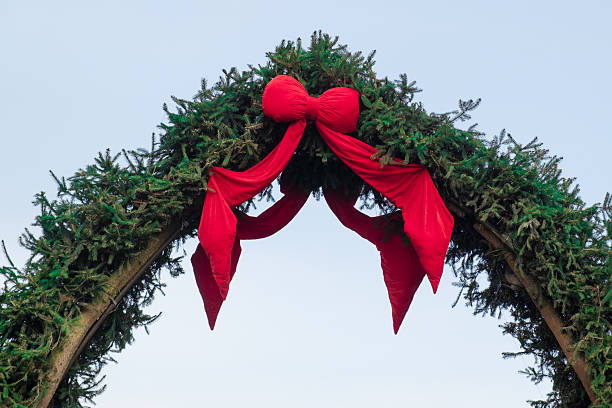istock Large evergreen arch decorated with bright red fabric bow and ribbons 2250554253