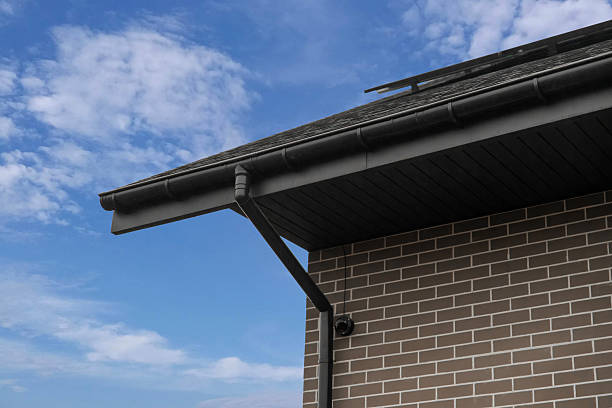 istock Black rain gutter system on brick house roof corner against sky 2250555645
