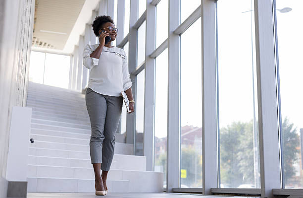 istock Businesswoman talking on phone walking through modern office building 2250555982