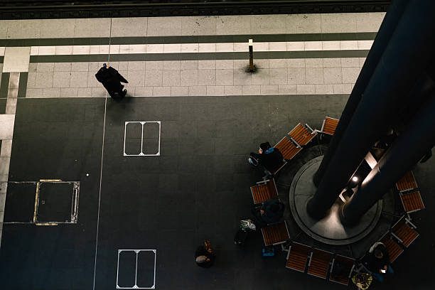 High angle view of commuters waiting in a modern train station with circular seating and platform details.