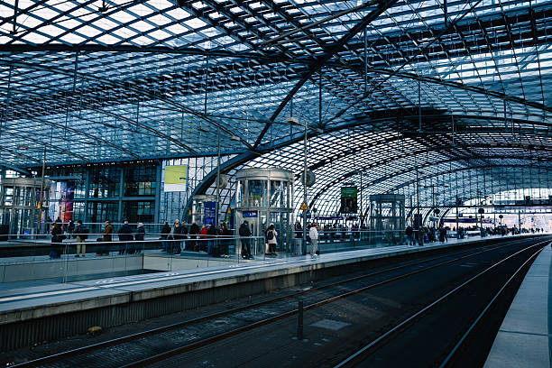 Travelers waiting at a platform inside a sleek, futuristic transportation hub.