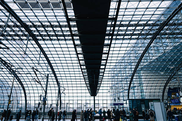 Travelers waiting at a platform inside a sleek, futuristic transportation hub.
