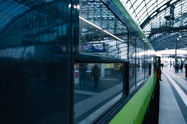 Close up view of a modern passenger train displaying reflections of the station interior on its window and exterior surface.