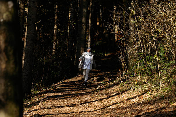 Caucasian female in forest pathway enjoying nature on a chilly day