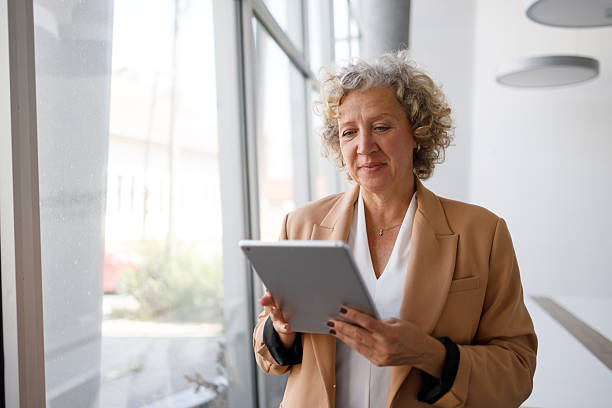 istock Mature businesswoman using digital tablet in modern office, focused on technology and communication 2250562218