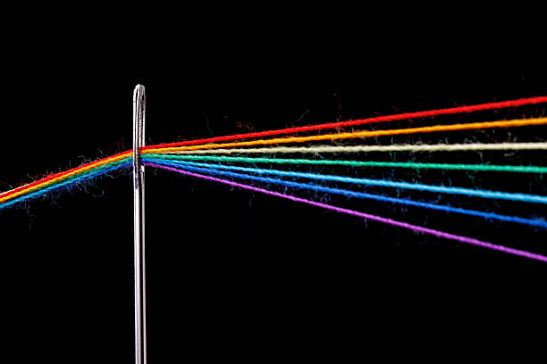 istock multi-colored threads for sewing in the form of a rainbow pass through an antique needle on a black background 2250568794