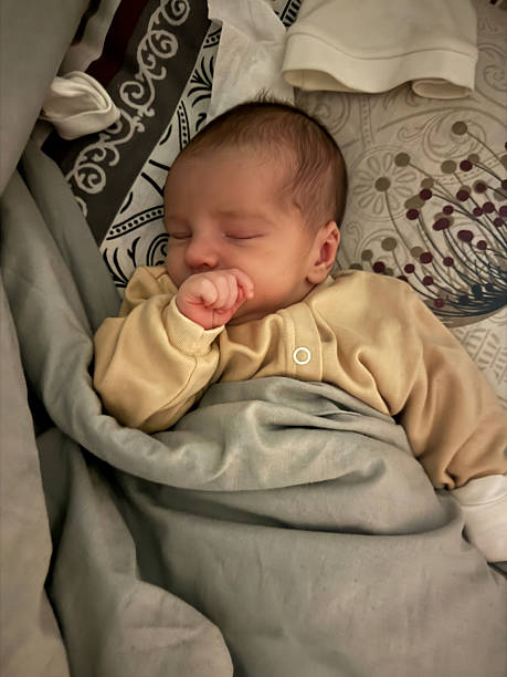 istock Newborn Baby Sleeping in Bed Wrapped in Blanket 2250570533