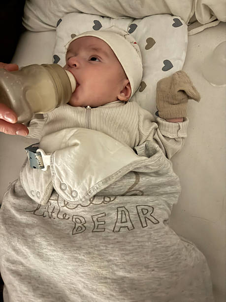 istock Baby Lying in Crib While Being Fed Milk with Bottle 2250571046