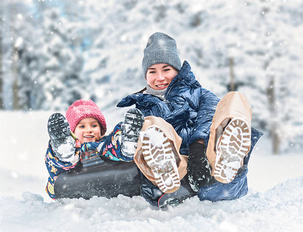 istock Happy mother and child sledding in snow 2250576341