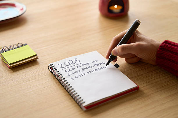 istock New year's resolutions. Hand starting 2026 goals indexed list in notebook 2250578619