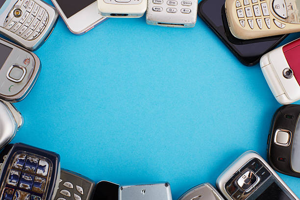 Various old mobile phones lined up side by side shaping a frame. Smartphones, push-button phones and flip phones, e-waste concept