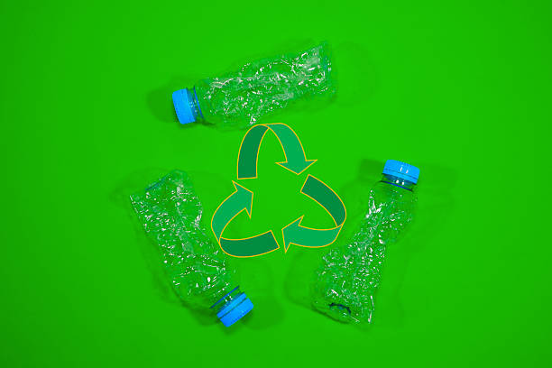 istock Three empty clear plastic water bottles arranged around a recycling symbol on a green background promoting sustainability efforts 2250580926