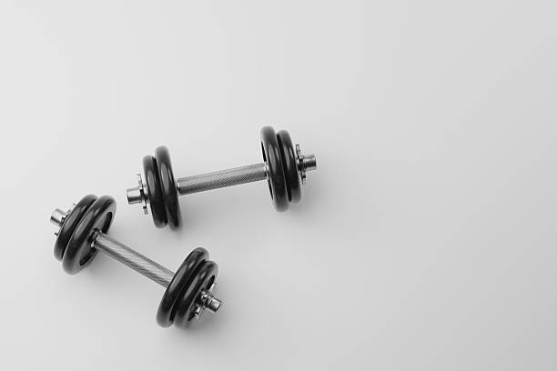 Pair of black adjustable dumbbells on a light gray background with copy space. Minimal fitness concept for strength training, home gym and workout equipment.