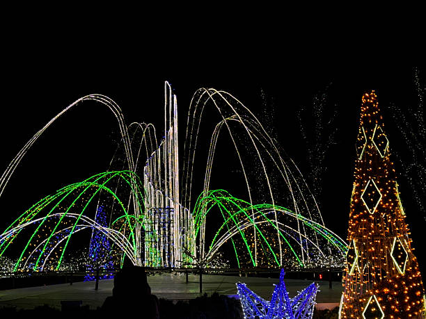 istock Large outdoor LED installation with green, white, blue, and orange light structures shaped like arches and cones 2250590384