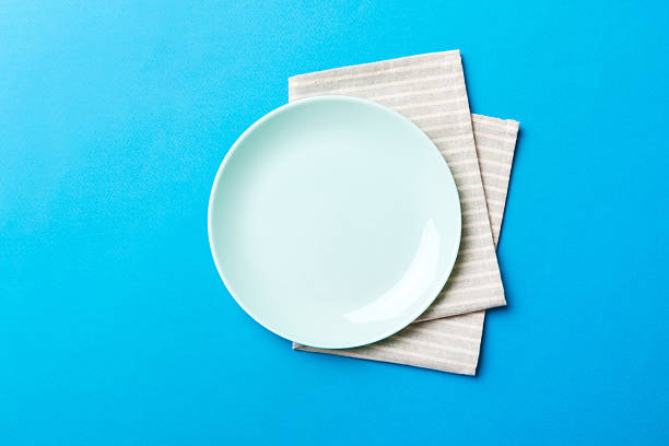 istock Top view on colored background empty round blue plate on tablecloth for food. Empty dish on napkin with space for your design 2250591313