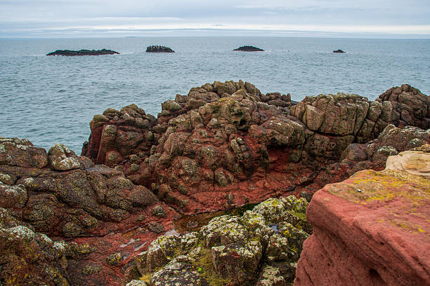Rocks and cliffs on the shore of the North Sea in East Lothian, Dunbar, small islands on the water and horizon over the water