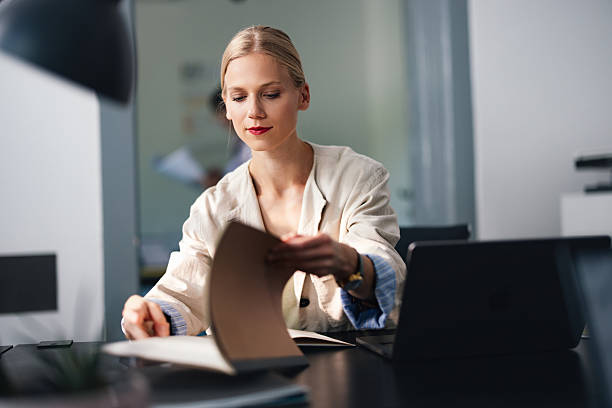 istock Professional Woman Organizing Documents at a Modern Desk in a Quiet Office Setting 2250601300
