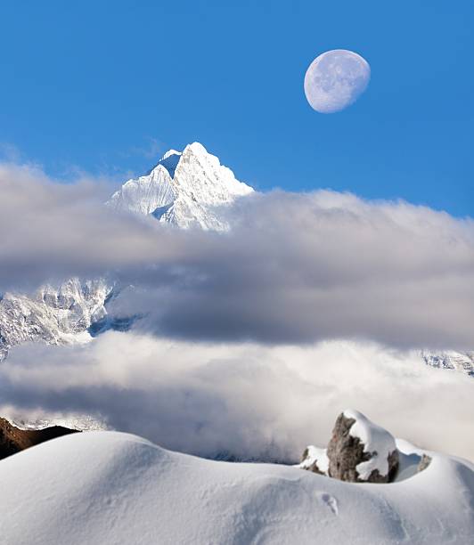 View of mount Thamserku in the middle of clouds and moon, Khumbu valley, Solukhumbu, Nepal Himalayas mountains
